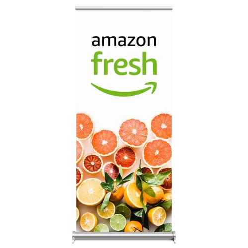 A vertical trade show banner displays 'amazon fresh' with a smile logo atop a vibrant background of citrus fruit slices.
